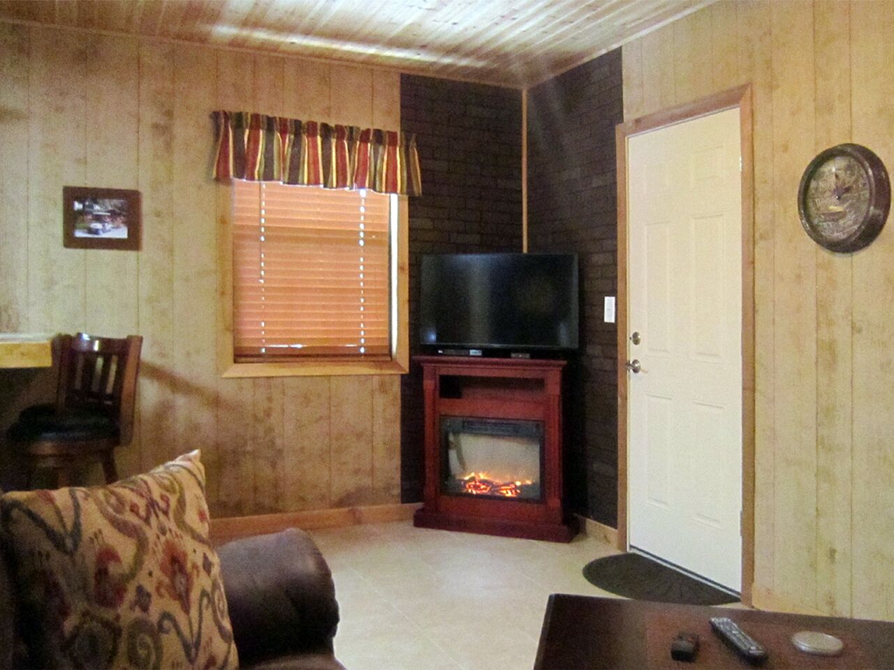 A living room with a fireplace, a television, and a door.