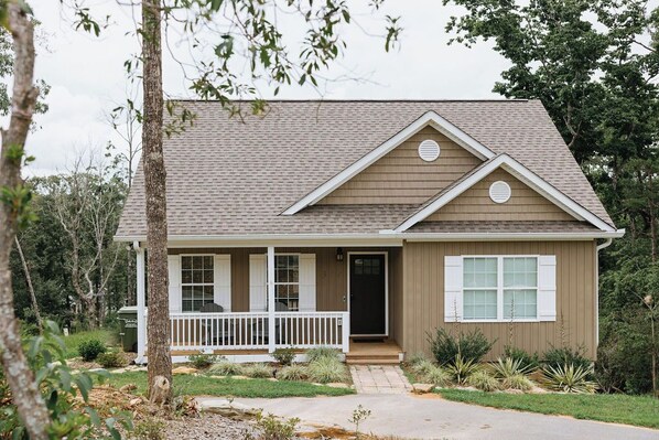 A single-story house with a front porch, a small deck, and a front yard with landscaping.