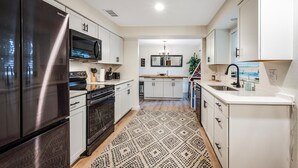 A modern kitchen with stainless steel appliances, white cabinetry, and a patterned rug. - Naples Florida (Naples)