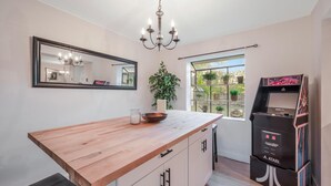 A kitchen with a wooden countertop, a mirror, a chandelier, a potted plant, and an Atari gaming console. - Naples Florida (Naples)
