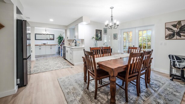 A modern kitchen with white cabinets, a black refrigerator, and a dining area with a wooden table and chairs. - Naples Florida (Naples)