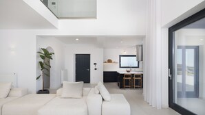 A modern living room with a sectional sofa, a potted plant, and a sliding glass door leading to a balcony.