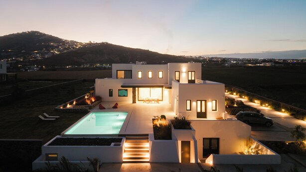 A modern house with a swimming pool, a patio, and a view of the surrounding landscape.