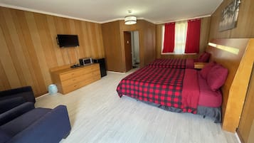 Cozy bedroom with a large bed, wooden paneling, and a flat-screen TV.