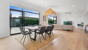 A modern dining area with a large table, chairs, and a hanging light fixture. - House Naomi - Martinborough Holiday Home (Martinborough)