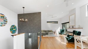 A modern living space with a glass partition, wooden flooring, a fireplace, and a dining area with green chairs. - Melmore Oasis - Cromwell Holiday Home (Cromwell)