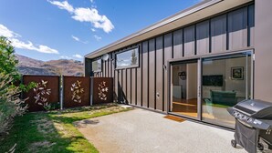 A modern house with a patio, a barbecue grill, and a view of the mountains. - Melmore Oasis - Cromwell Holiday Home (Cromwell)