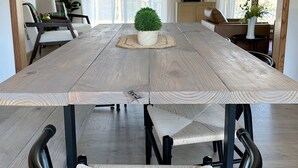 Un comedor con una gran mesa de madera, sillas de metal negro y una pequeña planta en maceta en el centro.