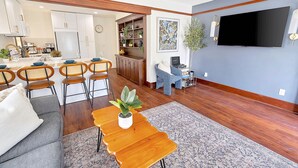 Una sala de estar moderna con comedor, suelo de madera y un televisor de pantalla plana montado en la pared.