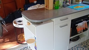 Una cocina compacta con una isla central, armarios de madera y piso estampado.