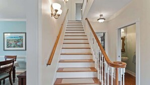 A staircase with wooden steps and white railings, leading to a landing with a light fixture. - Whispering Waves: Pool, Bikes & Walk to Beach (Melbourne Beach)