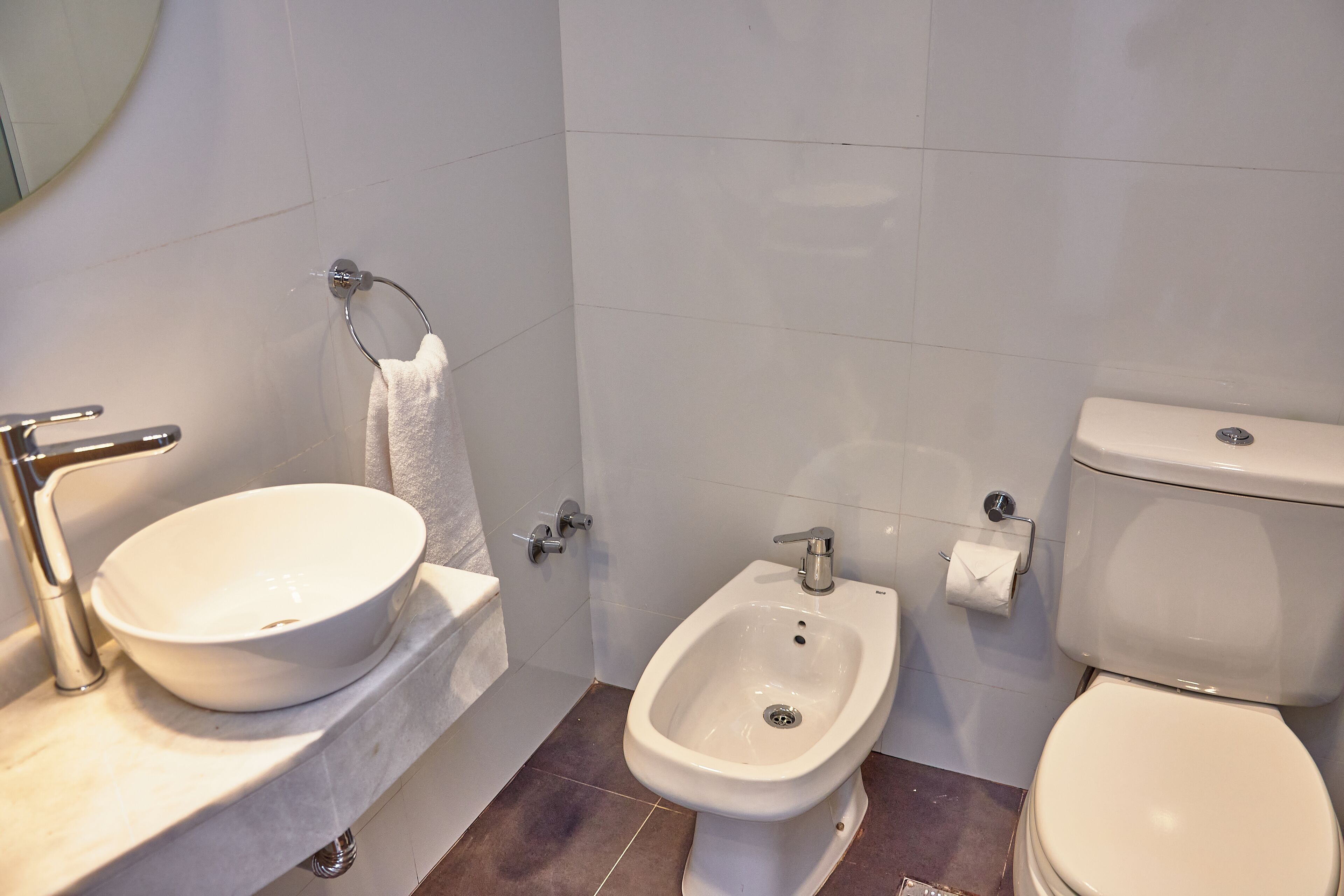 A bathroom with a sink, bidet, and toilet.