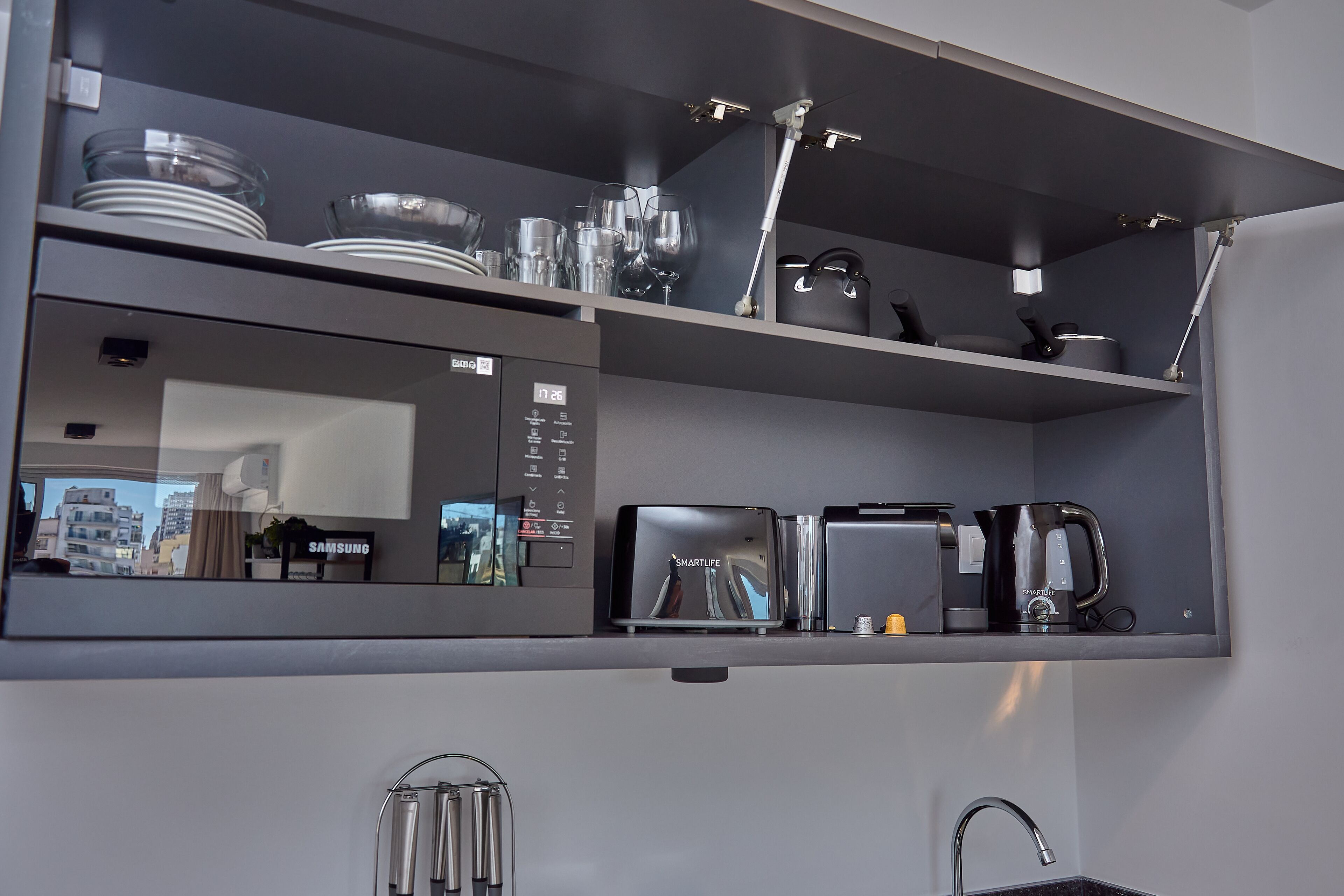 Eine moderne Küche mit integriertem Mikrowellenherd, Toaster und Kaffeemaschine auf einer grauen Arbeitsplatte.