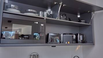Eine moderne Küche mit integriertem Mikrowellenherd, Toaster und Kaffeemaschine auf einer grauen Arbeitsplatte.