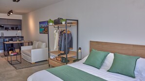 A modern hotel room with a bed, a seating area, a kitchenette, and a clothing storage unit. - Babel Campus (Buenos Aires)