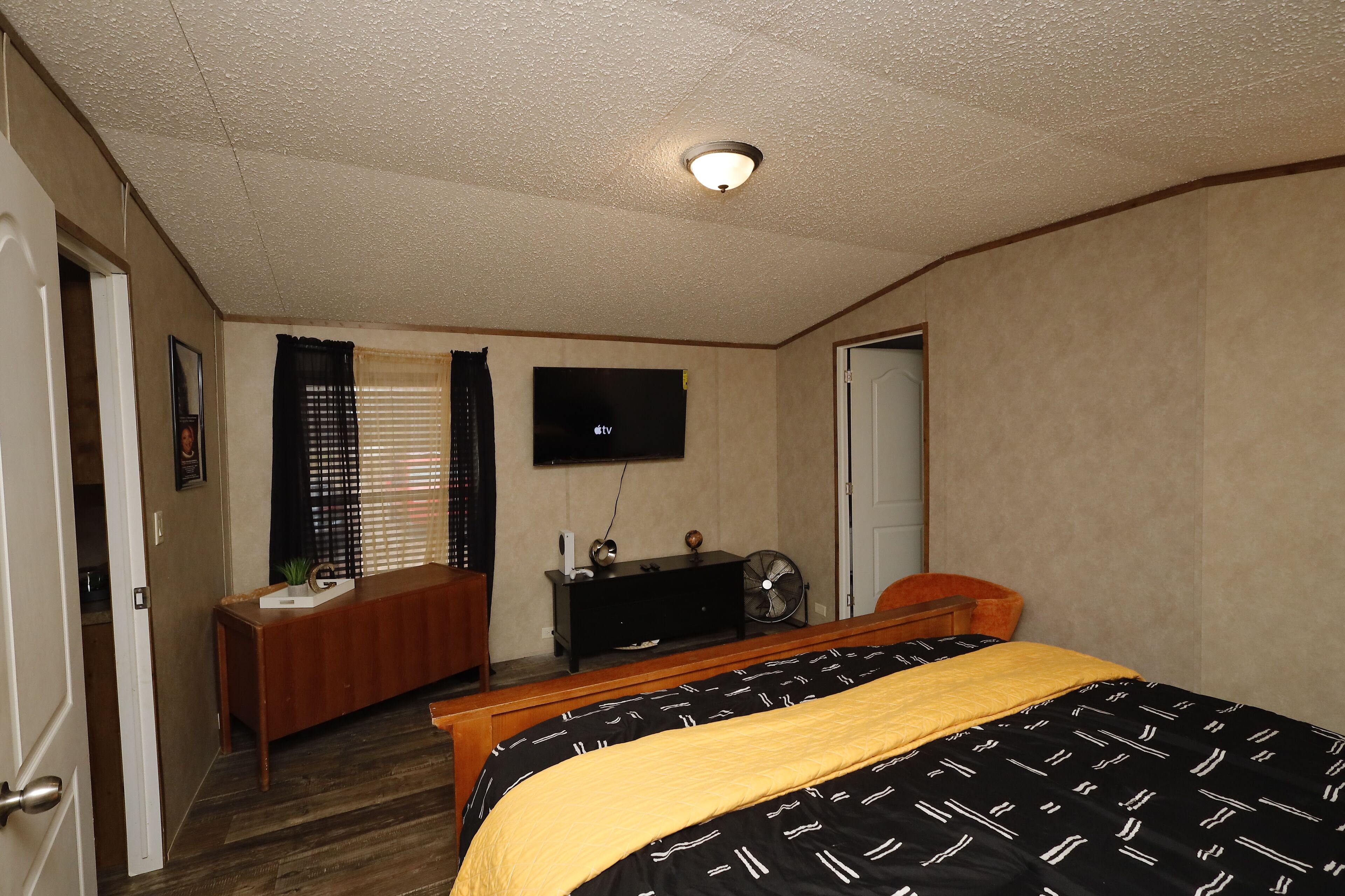A hotel room with a bed, a desk, a television, and a door.