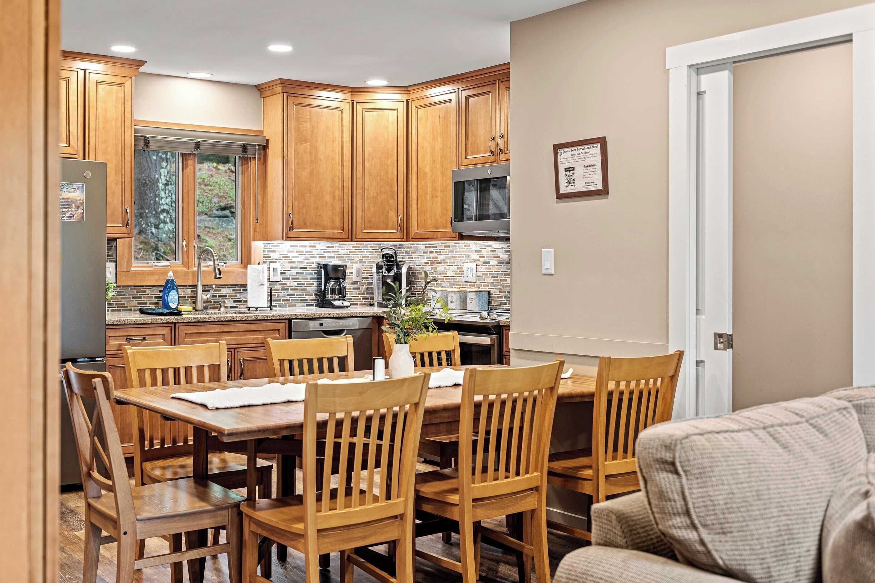 A modern kitchen with wooden cabinets, a dining area with wooden chairs, and a built-in microwave.