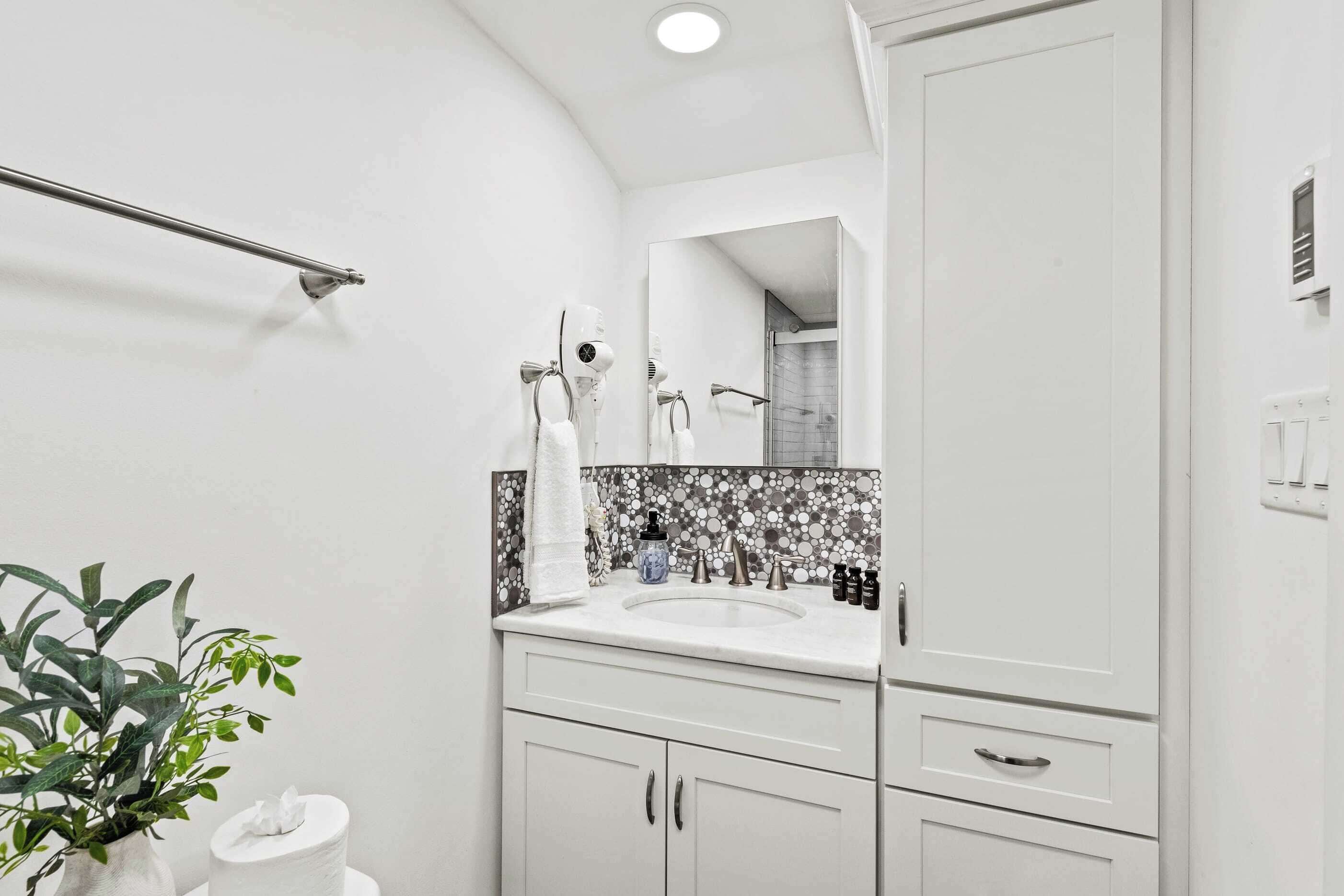 A modern bathroom with a white sink, a mirror, and a towel rack.