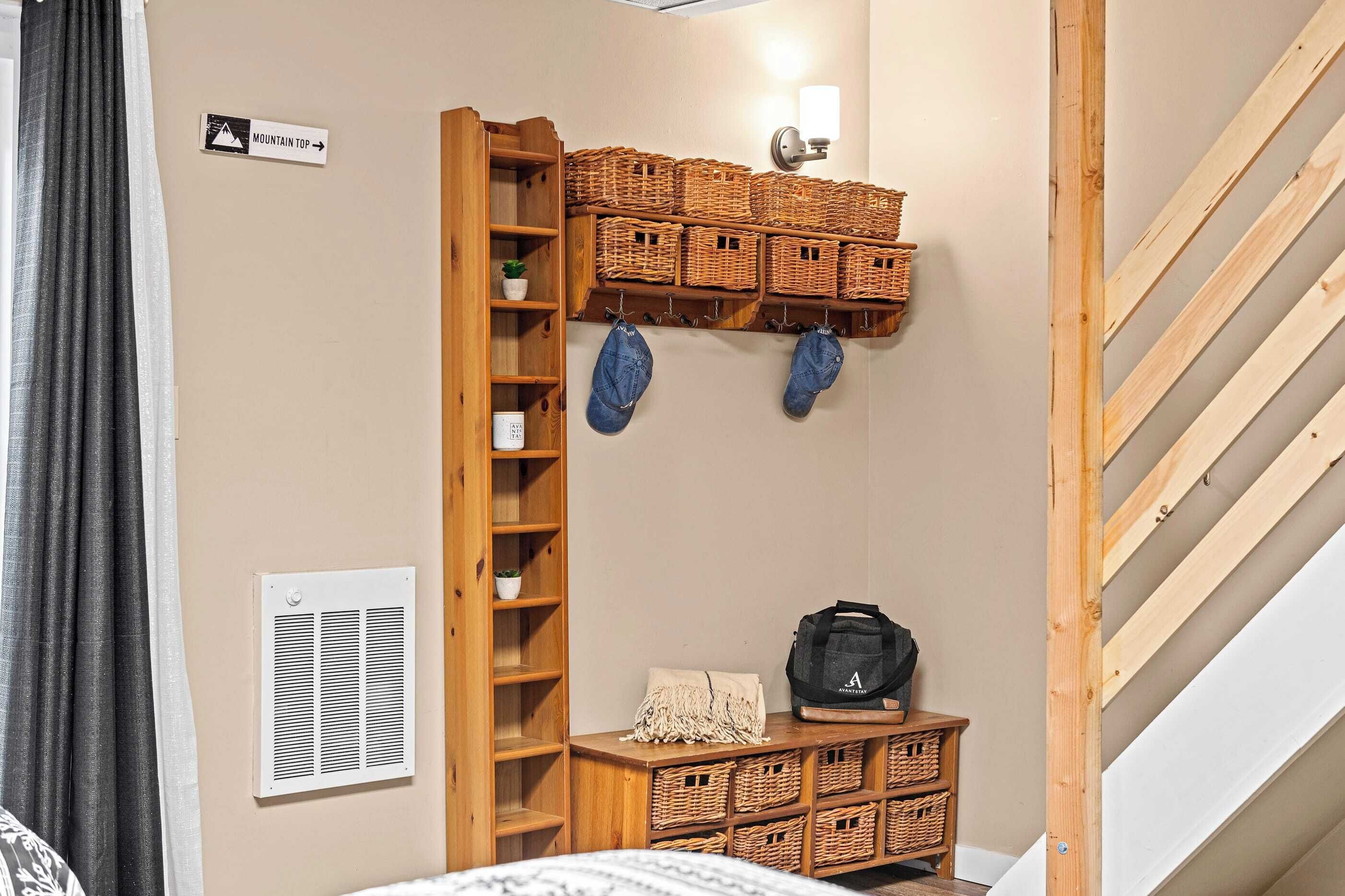 Une pièce avec une échelle en bois menant à une mezzanine, des paniers en osier sur des étagères, un luminaire fixé au mur et un panneau indiquant « SOMMET DE LA MONTAGNE ».