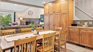 A spacious living room with a fireplace, wooden cabinets, and a dining area with a table and chairs. - Alpine Escape by Avantstay On Camelback Mountain, Near Waterpark/attractions (Tannersville)