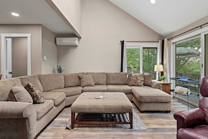 Un amplio salón con un sofá seccional grande, un reposapiés a juego y un sillón de cuero.