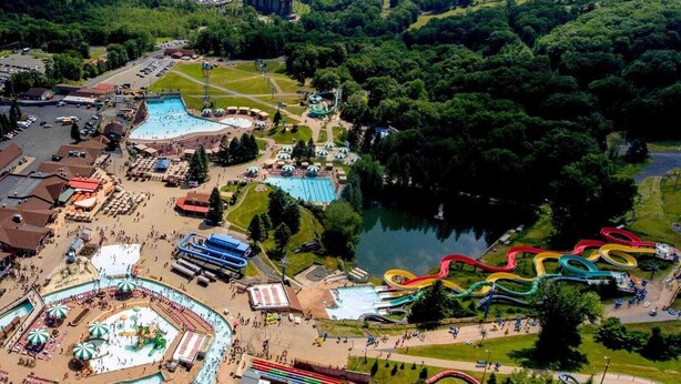 An aerial view of a theme park with multiple water slides, a large swimming pool, and various buildings. - Alpine Escape by Avantstay On Camelback Mountain, Near Waterpark/attractions (Tannersville)