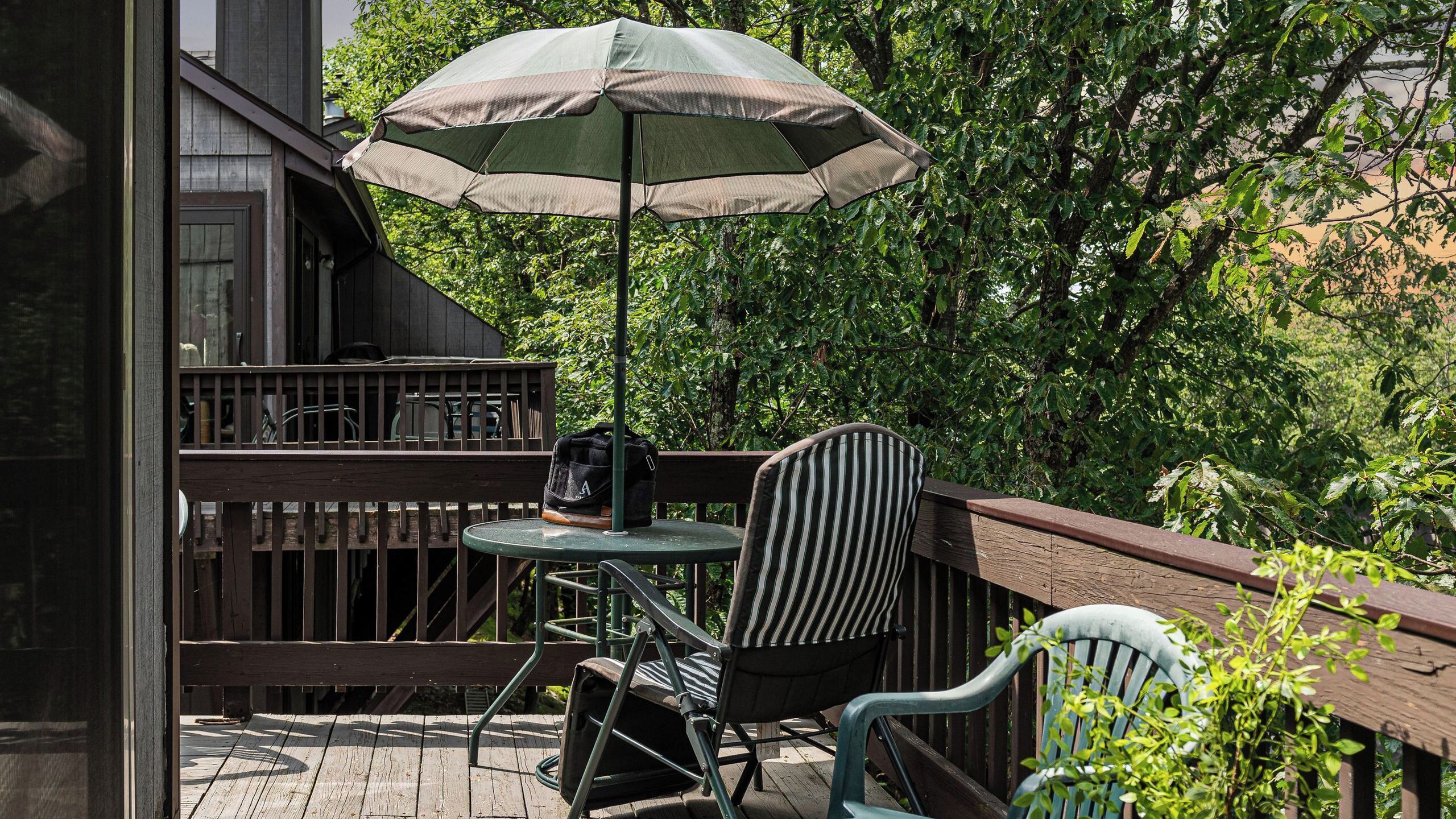 A wooden deck with a table and chairs, an umbrella, and a railing.