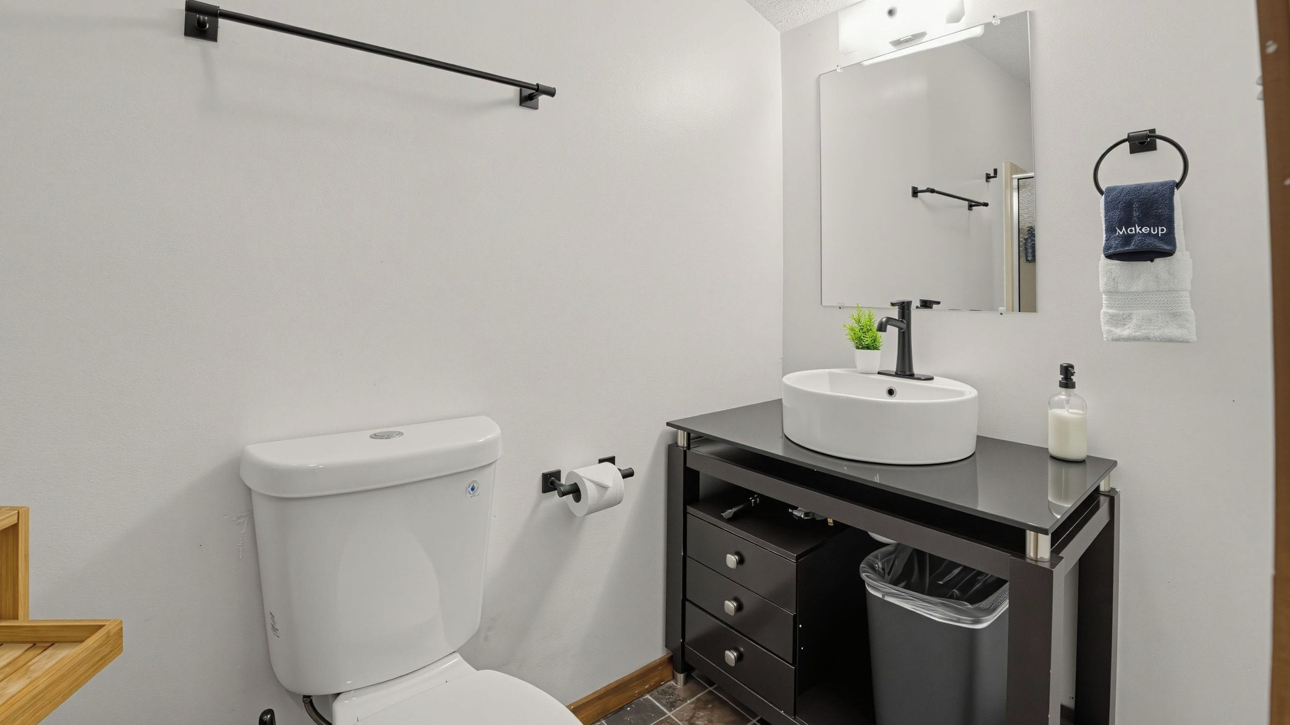 Une salle de bain moderne équipée de toilettes, d’un lavabo, d’un miroir et d’un porte-serviettes.