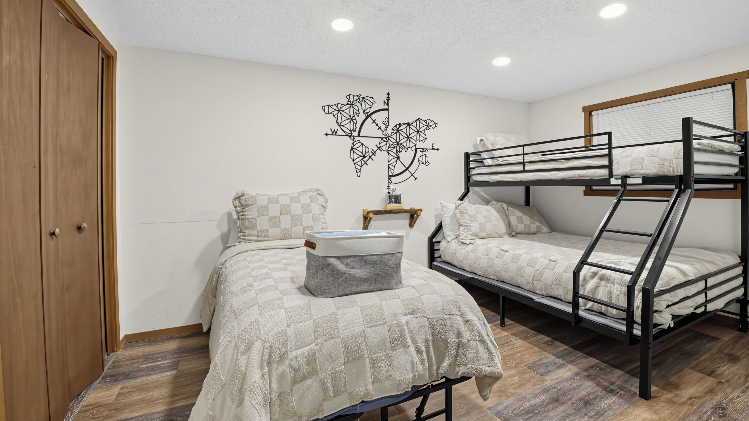 A bedroom with a bunk bed, a single bed, a wardrobe, and a wall decoration.
