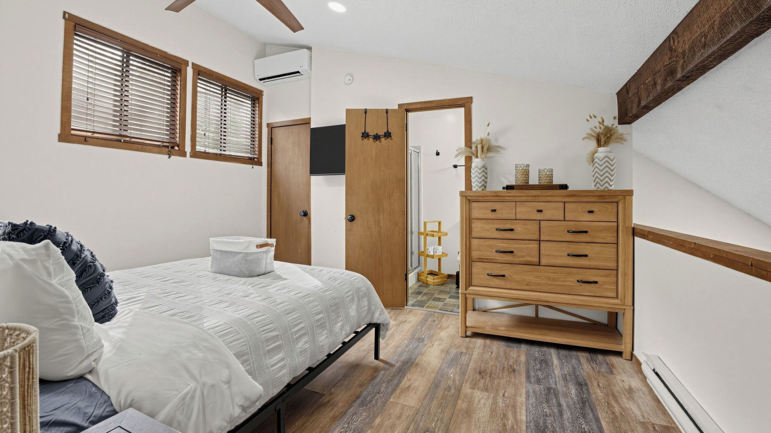 Una camera da letto con un letto, una cassettiera in legno e una porta che dà su un'altra stanza.