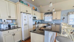 A kitchen with white cabinets, a refrigerator, a microwave, and a coffee station. - Waves 'n Wooder by Avantstay Swimspa + Game Room, Walk to Beach (Wildwood)