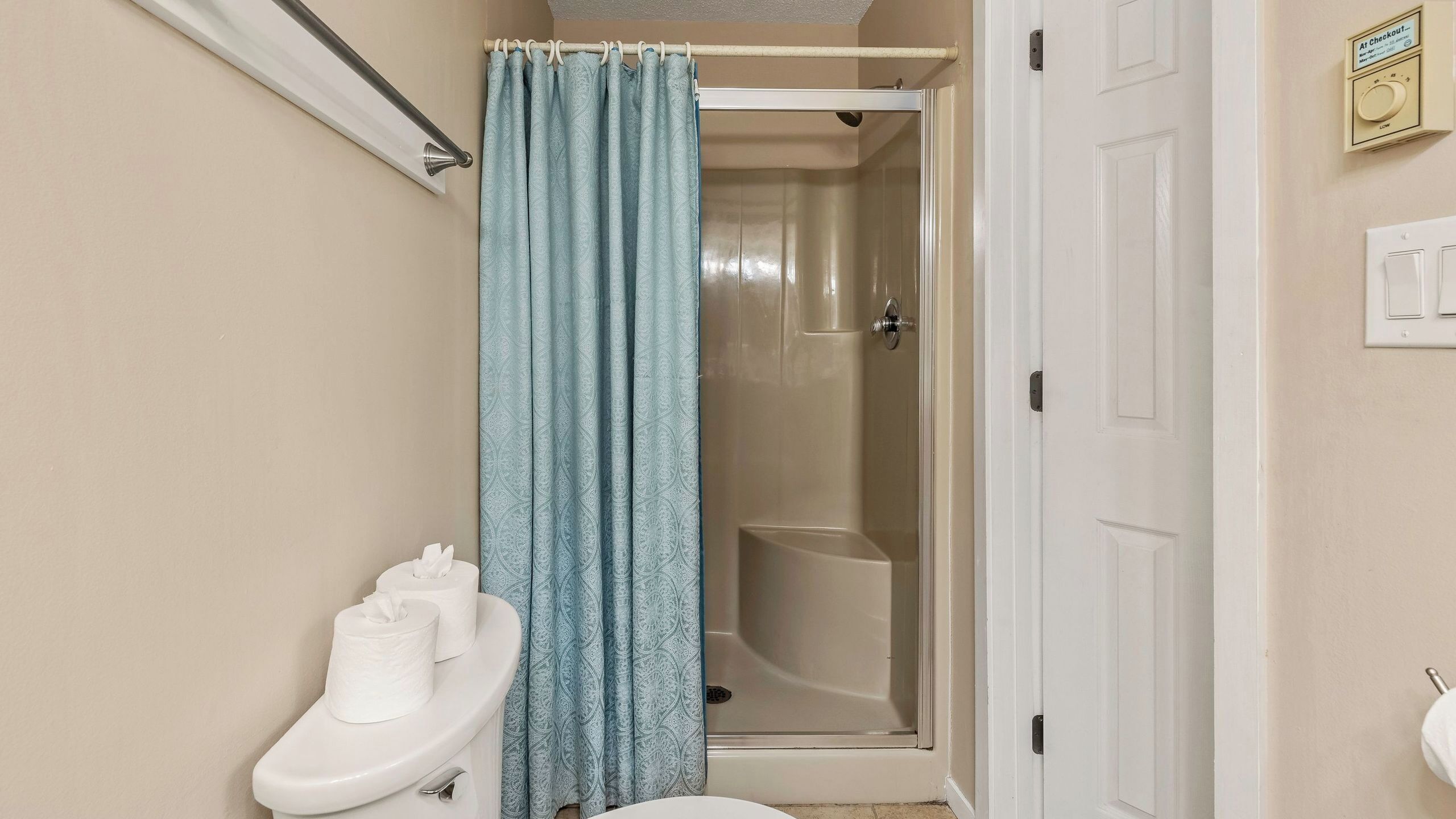 A bathroom with a toilet, a shower, and a white door.