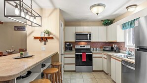 Una cocina moderna con una isla central, electrodomésticos de acero inoxidable y taburetes de madera.