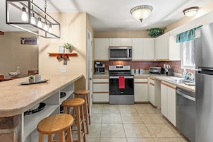 Una cocina moderna con una isla central, electrodomésticos de acero inoxidable y taburetes de madera.