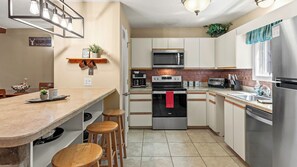 Una cocina moderna con una isla central, electrodomésticos de acero inoxidable y una lámpara colgante.