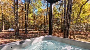 A hot tub in a forested area with trees and a car in the background. - The Breck by Avantstay Modern 6bdr Cabin w/ Hot Tub & Game Room (Lake Harmony)