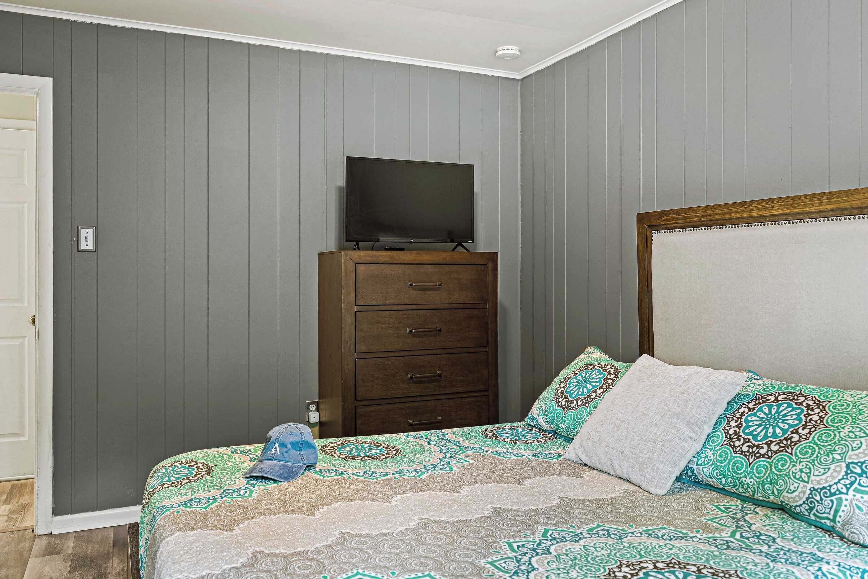 A bedroom with a bed, a dresser, and a television on top of it.