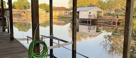 A wooden dock extending over a calm body of water, with a green hose coiled on the dock.