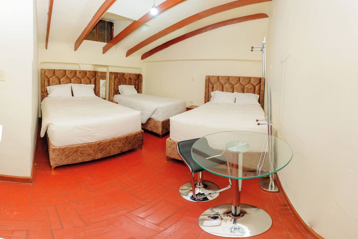A hotel room with two beds, a glass table, and a red herring floor.