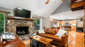 A modern living room with a stone fireplace, leather sofa, and wooden coffee table. - Highland Cabin, pets ok/GW Nat'l Forest/near JMU (Hinton)