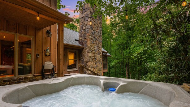 A hot tub with a stone pillar, surrounded by lush greenery. - Highland Cabin, pets ok/GW Nat'l Forest/near JMU (Hinton)