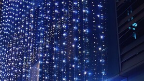 A hotel with a red sign reading "VENTUS by Delmont" and a large building adorned with numerous blue lights. - Hotel The Ventus - A boutique Hotel  (New Delhi)