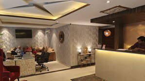A modern reception area with a reception desk, seating area, and a wall-mounted television. - Hotel The Ventus - A boutique Hotel  (New Delhi)