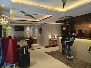 A modern hotel lobby with a reception desk, seating area, and a clock. - Hotel The Ventus - A boutique Hotel  (New Delhi)