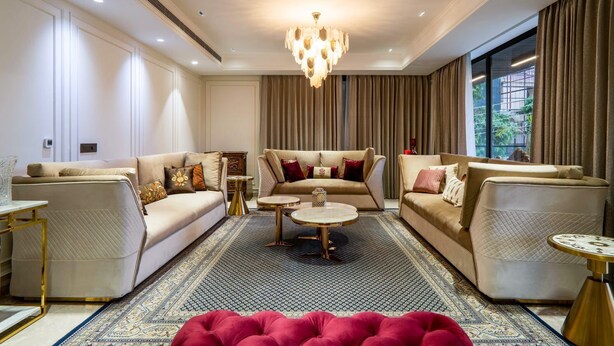 A modern living room with two sofas, a coffee table, and a red ottoman. - Hotel The Ventus - A boutique Hotel  (New Delhi)