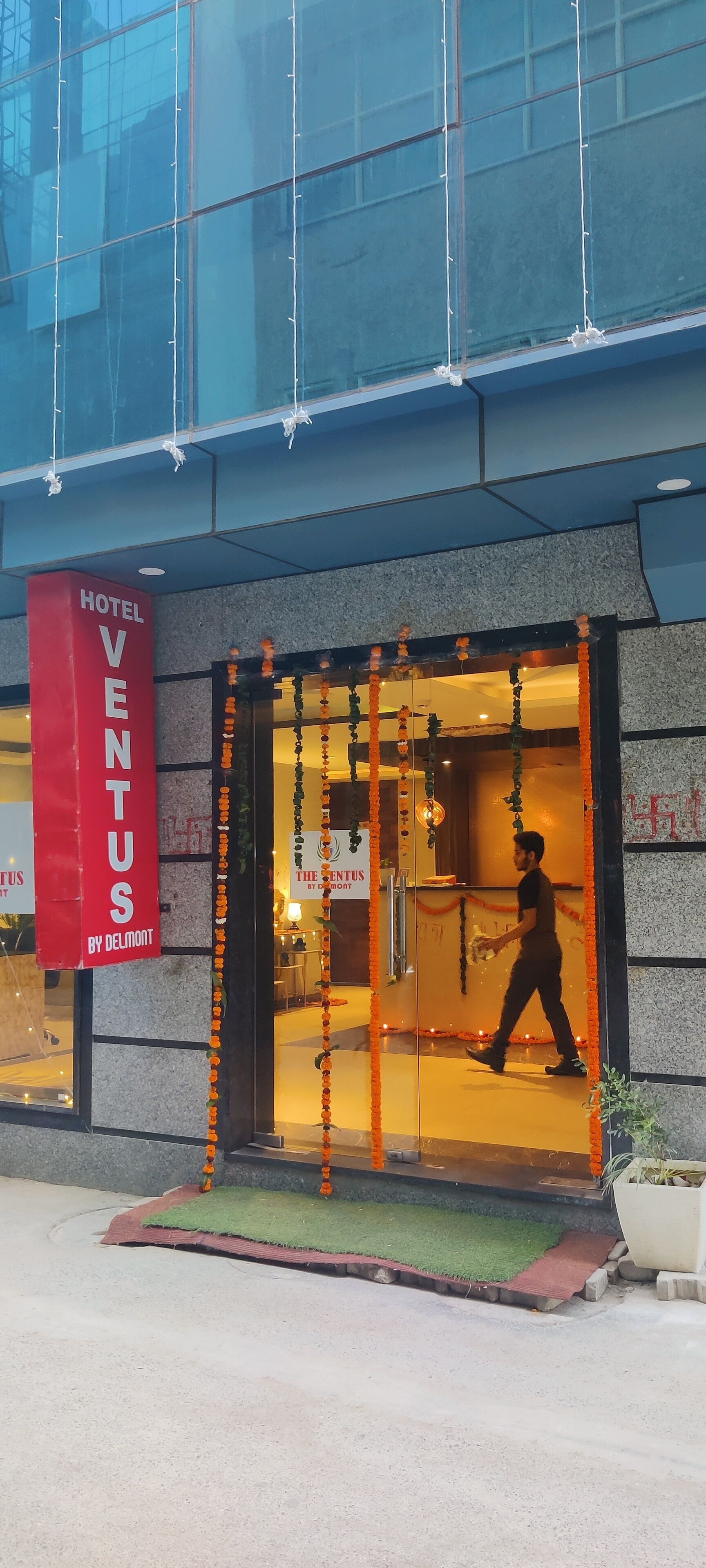 A hotel entrance with a glass door, a red banner, and a person walking inside.
