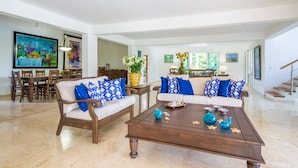 A spacious living room with two sofas, a coffee table, and a dining area with wooden furniture. - Linksview Retreat, Casa de Campo (La Romana)