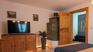 A room with a wooden cabinet, a television, a potted plant, and a bench. - Stylish and cozy holiday home in Klais with terrace and garden, near MIttenwald. (Krün)