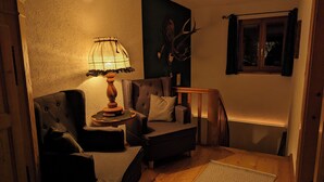 A cozy living room with a sofa, armchair, and a lamp. There's a wooden floor and a patterned rug. - Stylish and cozy holiday home in Klais with terrace and garden, near MIttenwald. (Krün)
