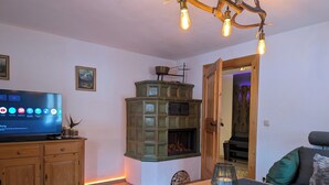 A cozy living room with a television, wooden furniture, a fireplace, and a modern light fixture. - Stylish and cozy holiday home in Klais with terrace and garden, near MIttenwald. (Krün)